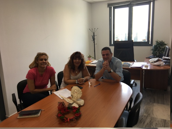 Three people are sitting around a table in an office.